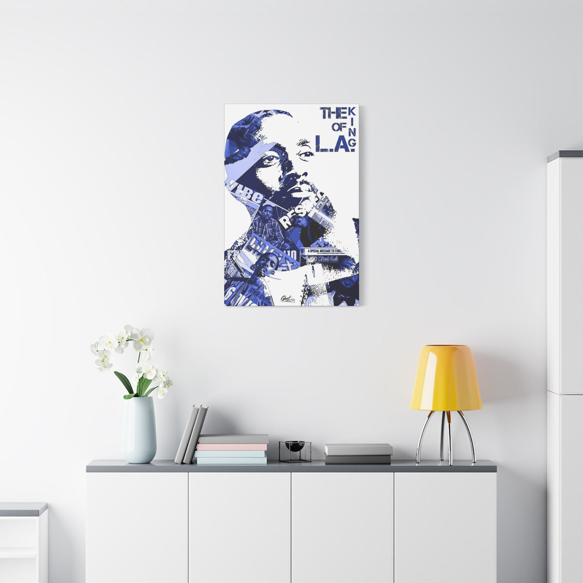 Crown of the Coast small canvas above a white sideboard and yellow lamp, blue collage portrait on white with bold text