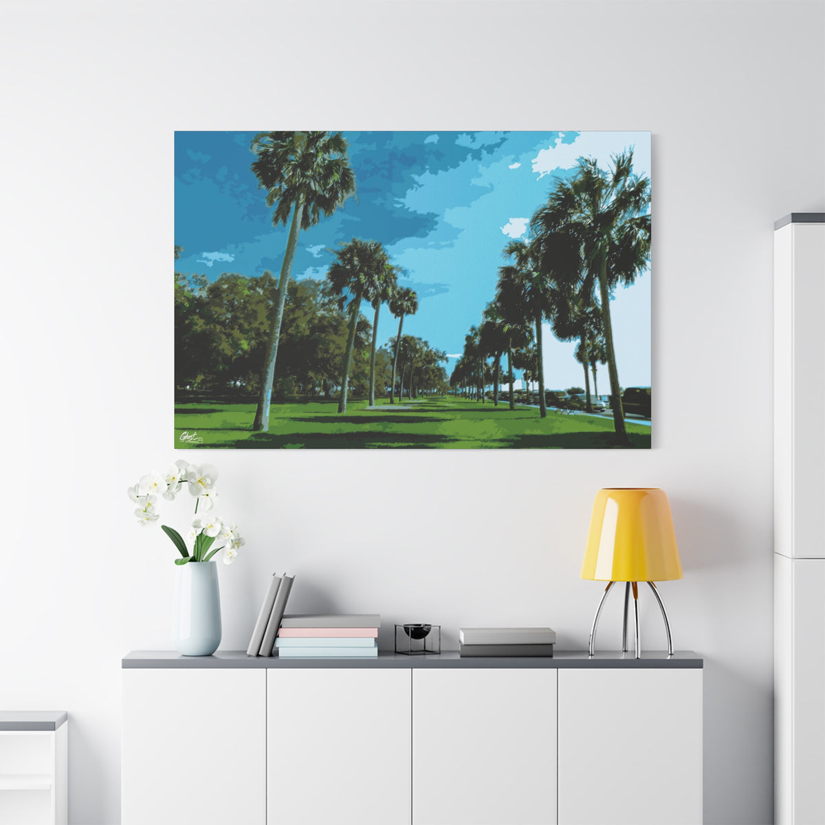 The Battery (Original) large canvas above a white sideboard and yellow lamp, sunlit palms and long shadows by the water