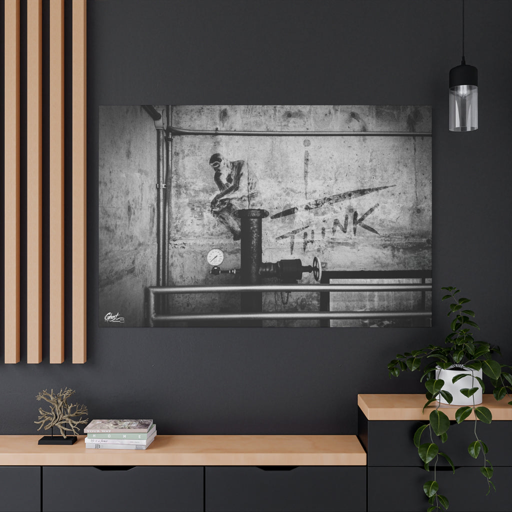 I Overthink canvas on a charcoal wall by wood slats, stenciled THINK with pipes and gauges on concrete, black and white