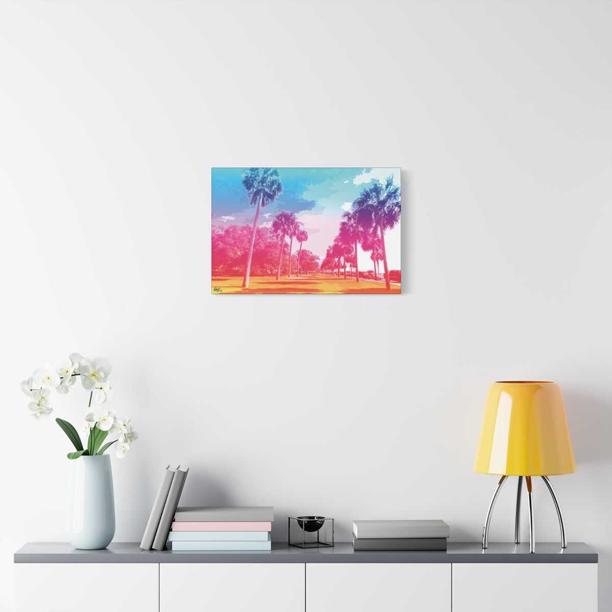 The Battery Tropical Edition medium canvas over a console with white flowers, palms in a pink and turquoise sunset