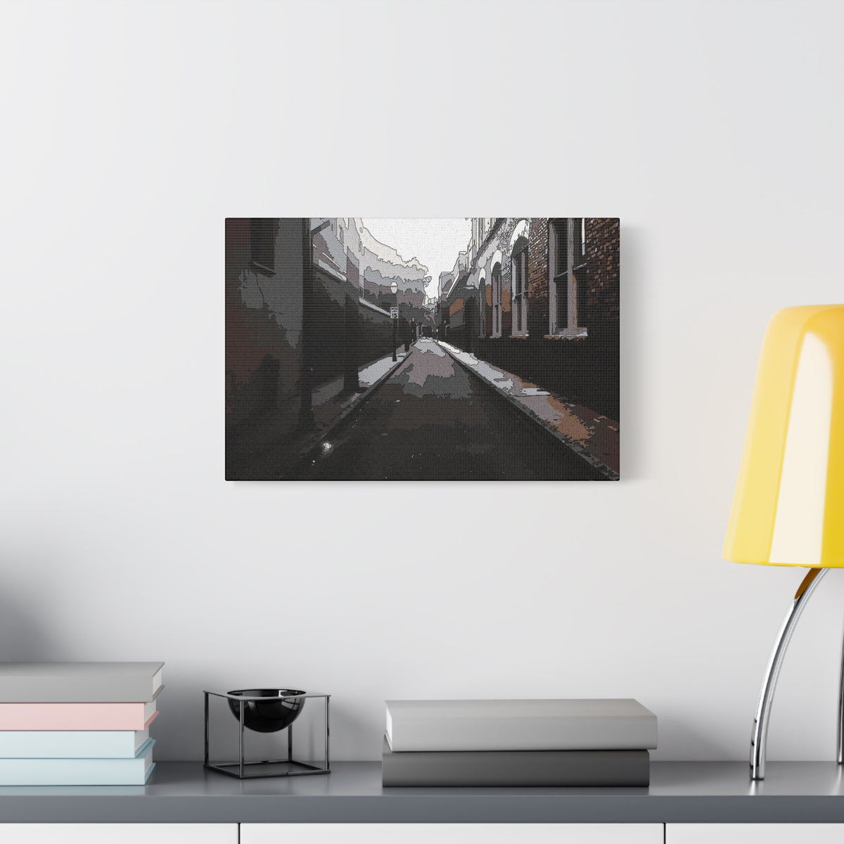 Charleston One Way oversized canvas beside a yellow desk lamp, moody alley with old brick walls and long shadows