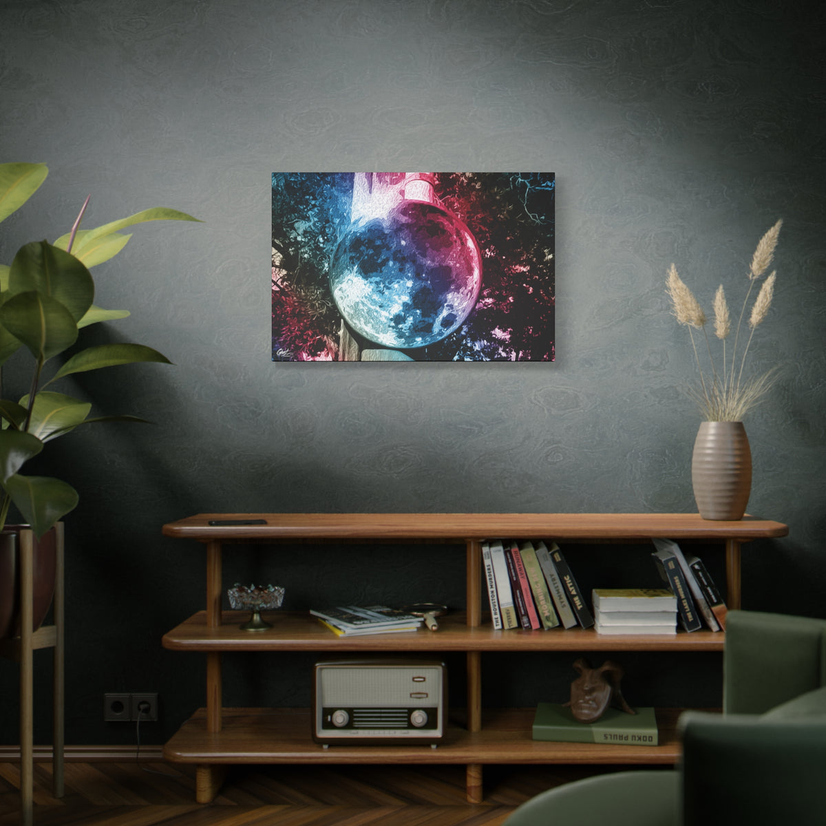 Universe in a Mirror canvas on a green-gray wall over bookshelves, moon-like orb in blue and pink film tones in a surreal sky
