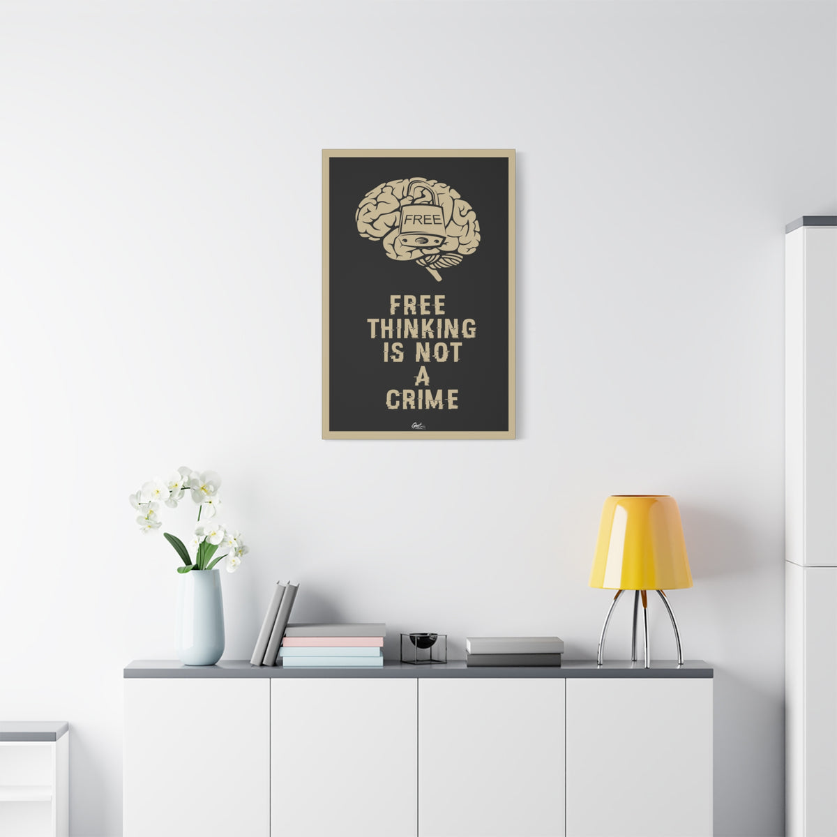Free Thinking Is Not a Crime small canvas above a white sideboard and yellow lamp, padlocked brain in beige on charcoal