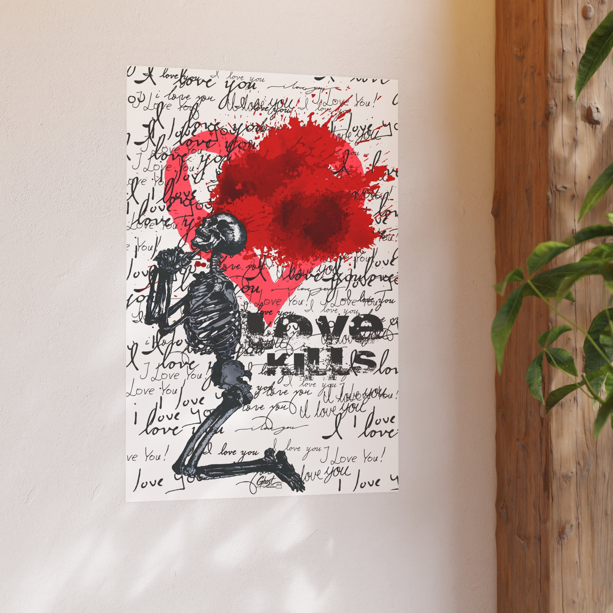 Medium Love Kills art poster on a warm white wall beside a wood post and plant