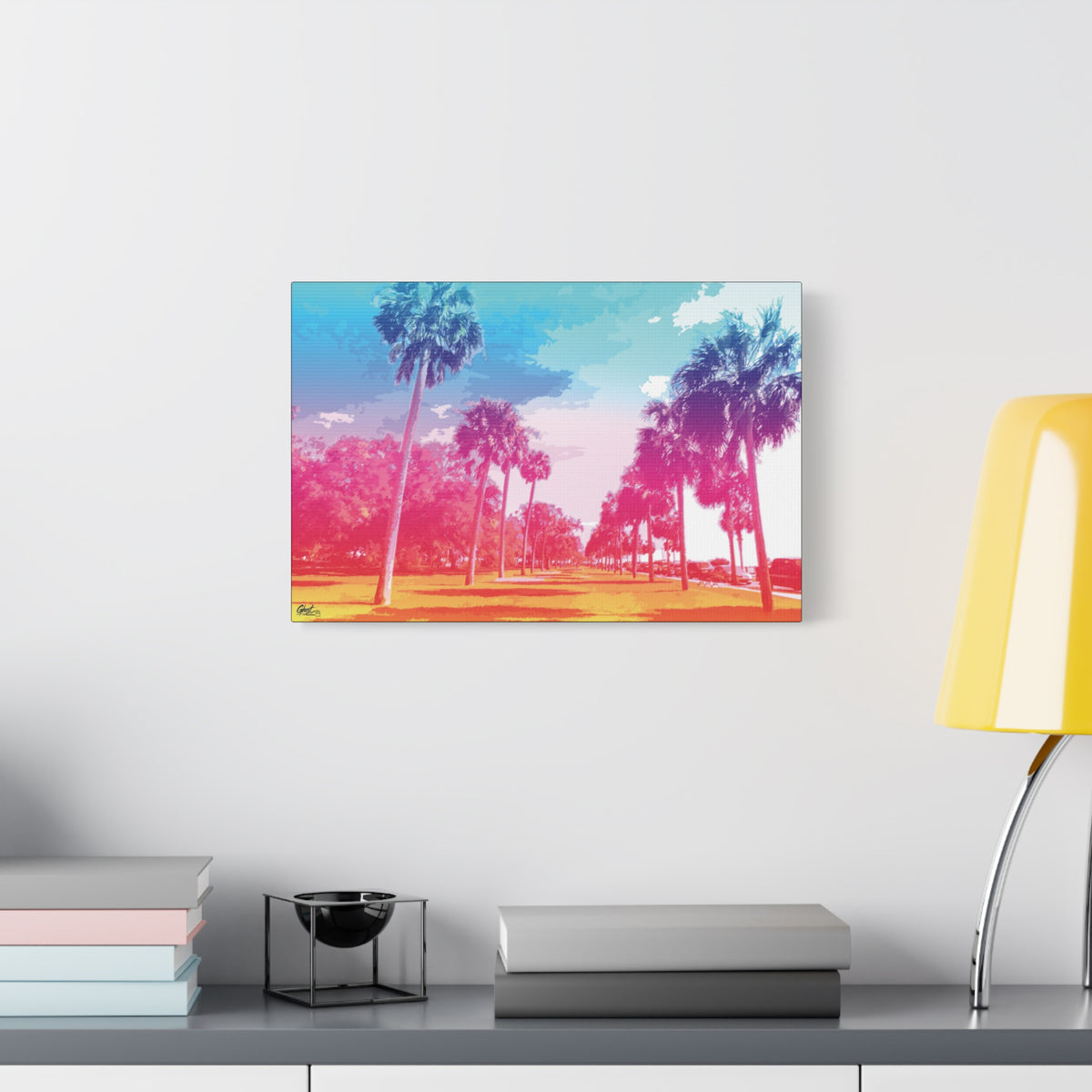 The Battery Tropical Edition canvas beside a yellow desk lamp, palm silhouettes against a turquoise, pink and gold sunset