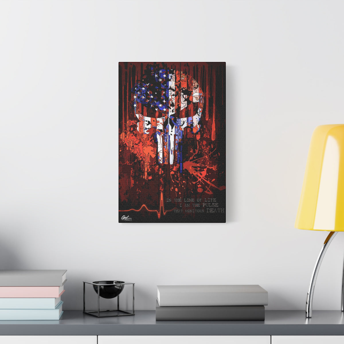 The Vigilante large canvas beside a yellow desk lamp, skull emblem built from a distressed American flag