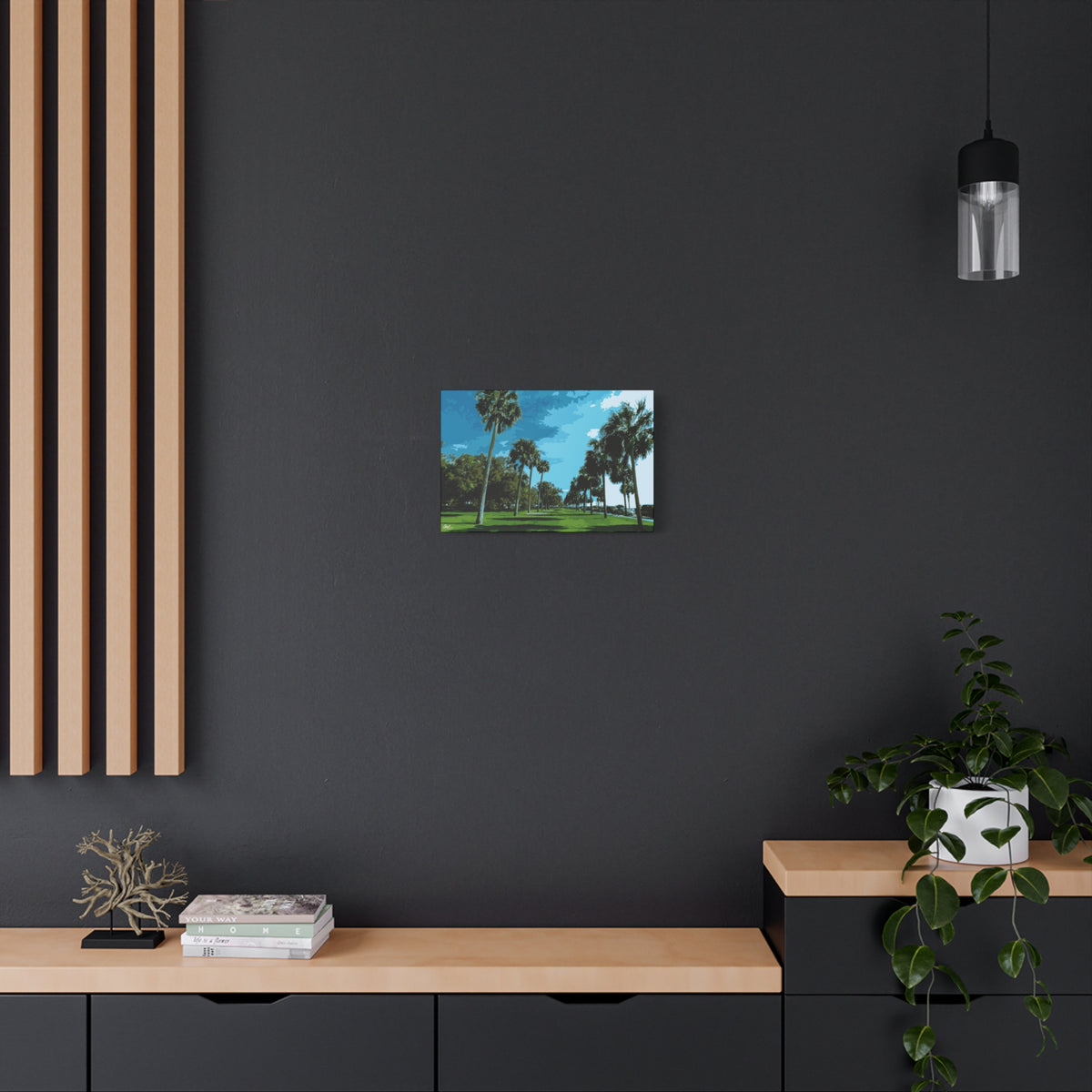 The Battery (Original) small canvas on a charcoal wall over an oak shelf, sunlit palms and long shadows by the water
