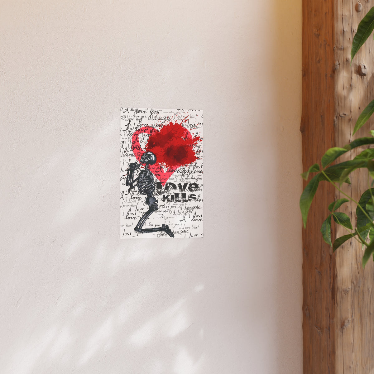 Small Love Kills poster on a warm white wall beside a wood post and plant