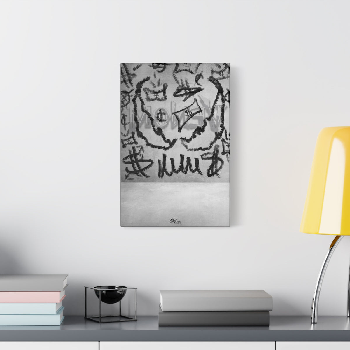 We Are Money small canvas beside a yellow desk lamp, graffiti-style black marks and tags on a pale base