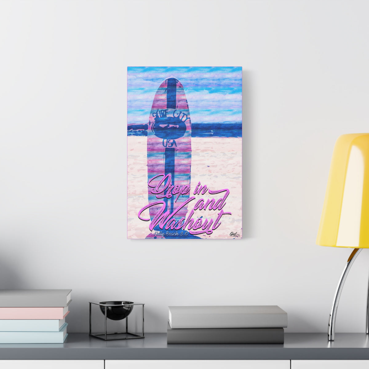 Drop In and Wash Out, Folly Beach medium canvas beside a yellow desk lamp, sun-bleached surfboard art in soft pinks and blues