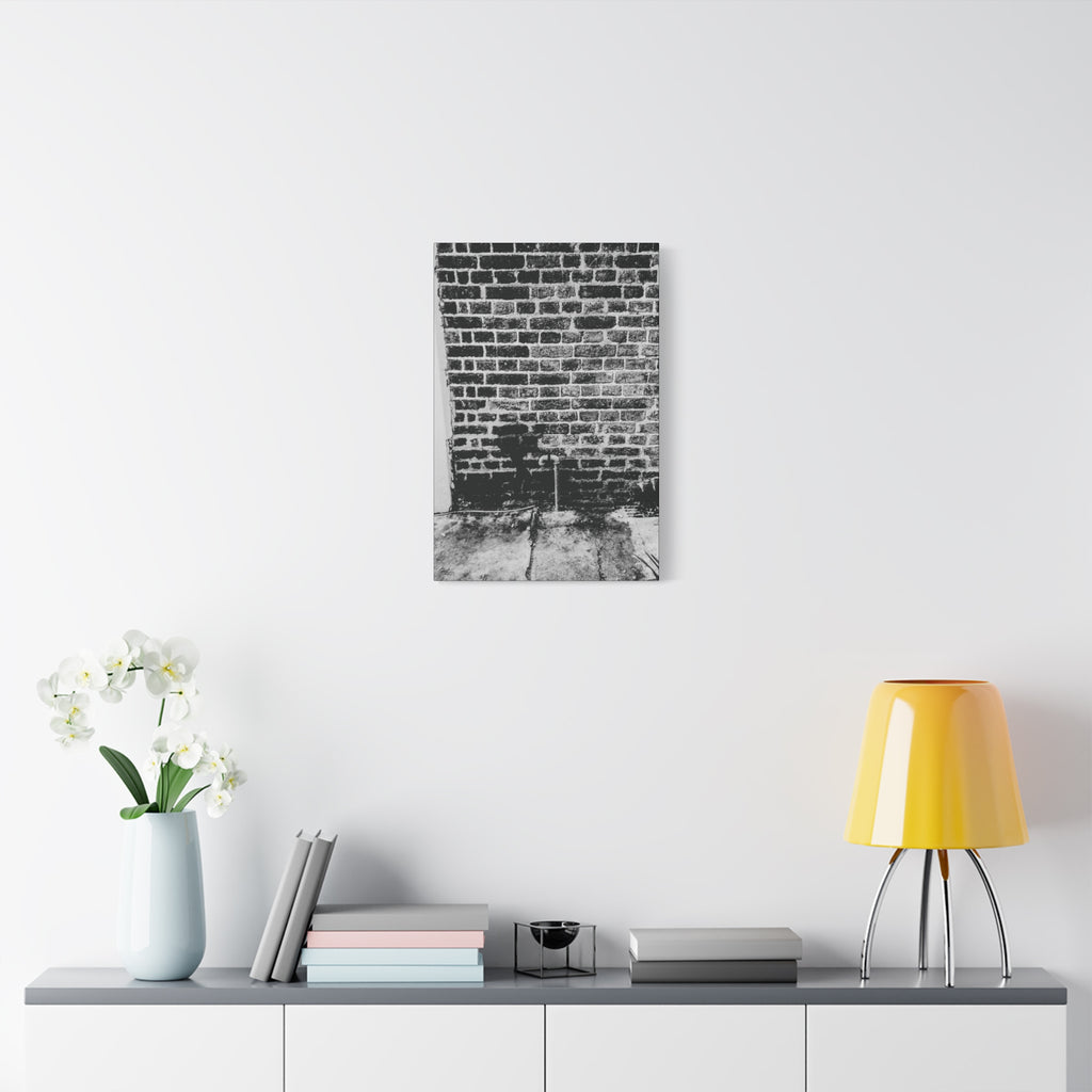 A Little Hiking in Charleston canvas over a console with white flowers, high-contrast brick wall with a tiny stencil hiker