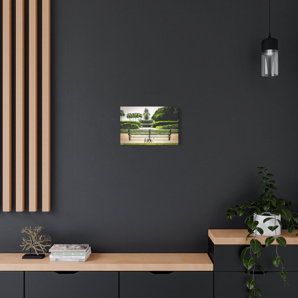 Pineapple Crossing canvas on a charcoal wall over an oak shelf, painterly park scene with the pineapple fountain