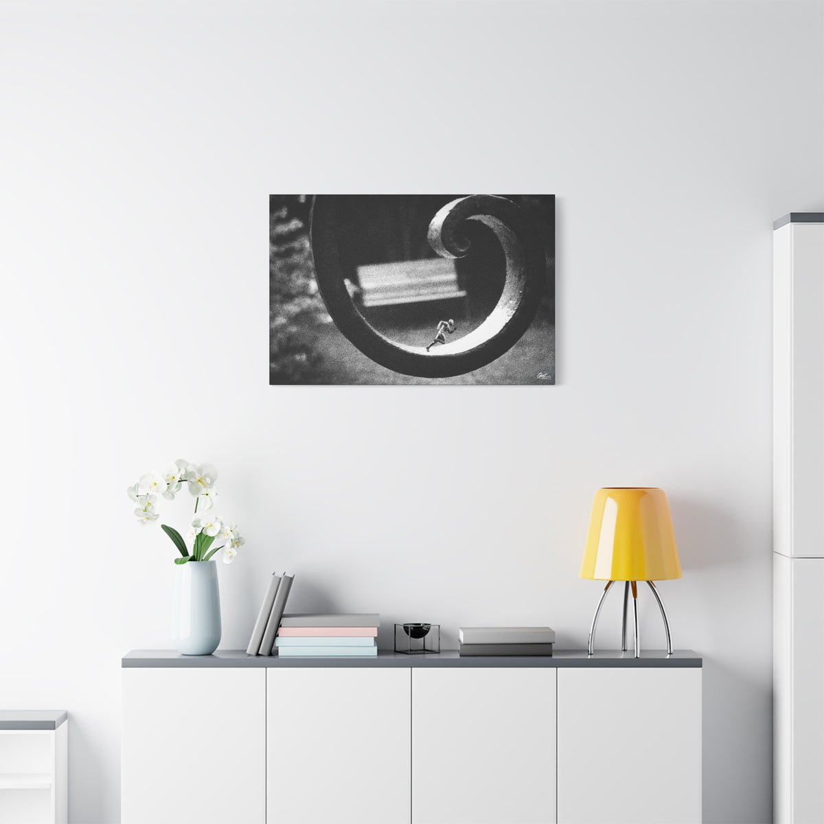 A Man in Charleston small canvas above a white sideboard and yellow lamp, tiny running figure inside a curled wrought-iron scroll in grainy black and white