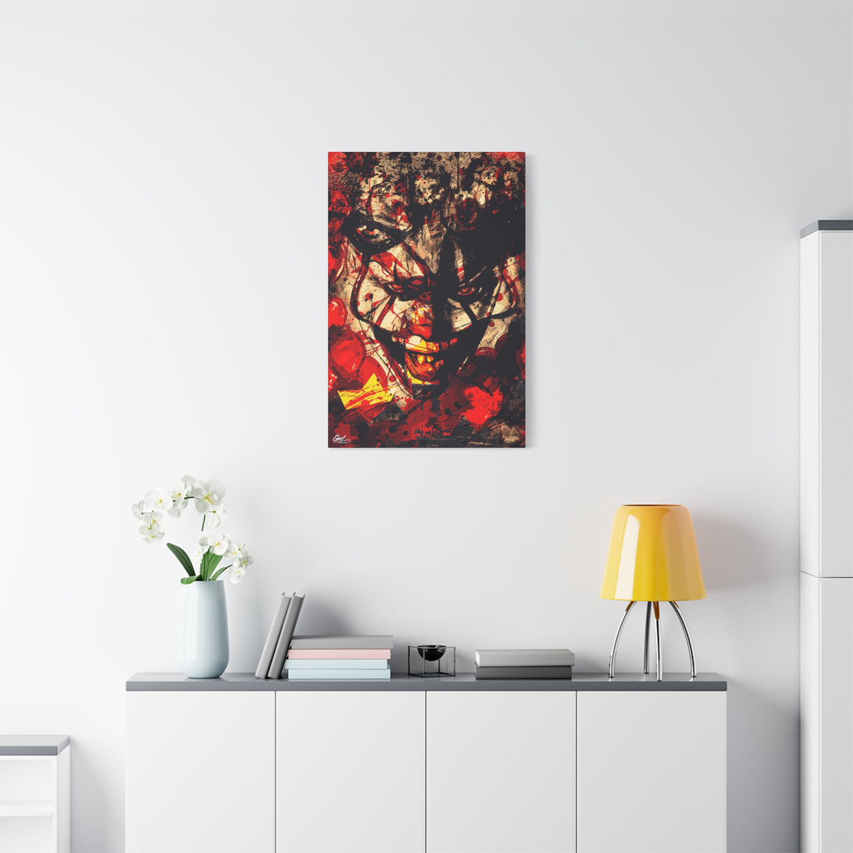 Down in a Drain small canvas above a white sideboard and yellow lamp, leering clown face in distressed red, black and cream
