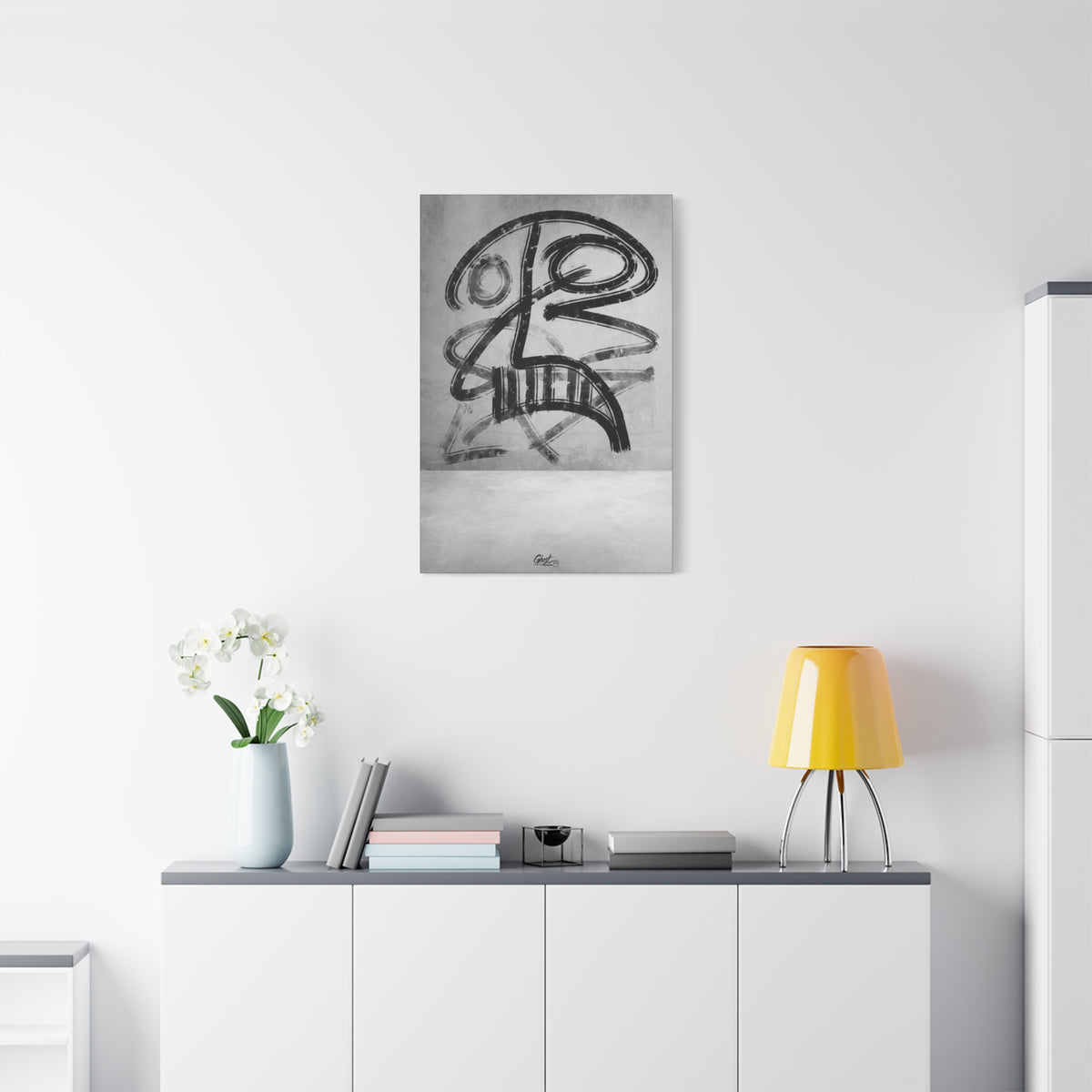 The Mask small canvas above a white sideboard and yellow lamp, bold black brushstroke mask-like figure on a gray field