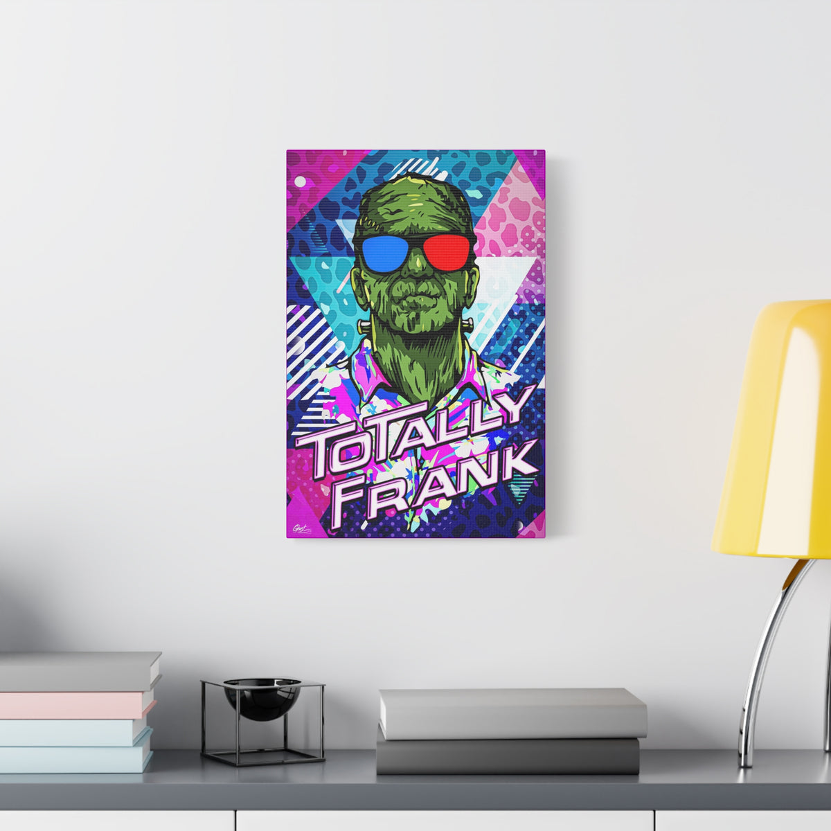 Monster Vibes medium canvas beside a yellow desk lamp, green monster in red-and-blue 3D glasses and a tropical shirt