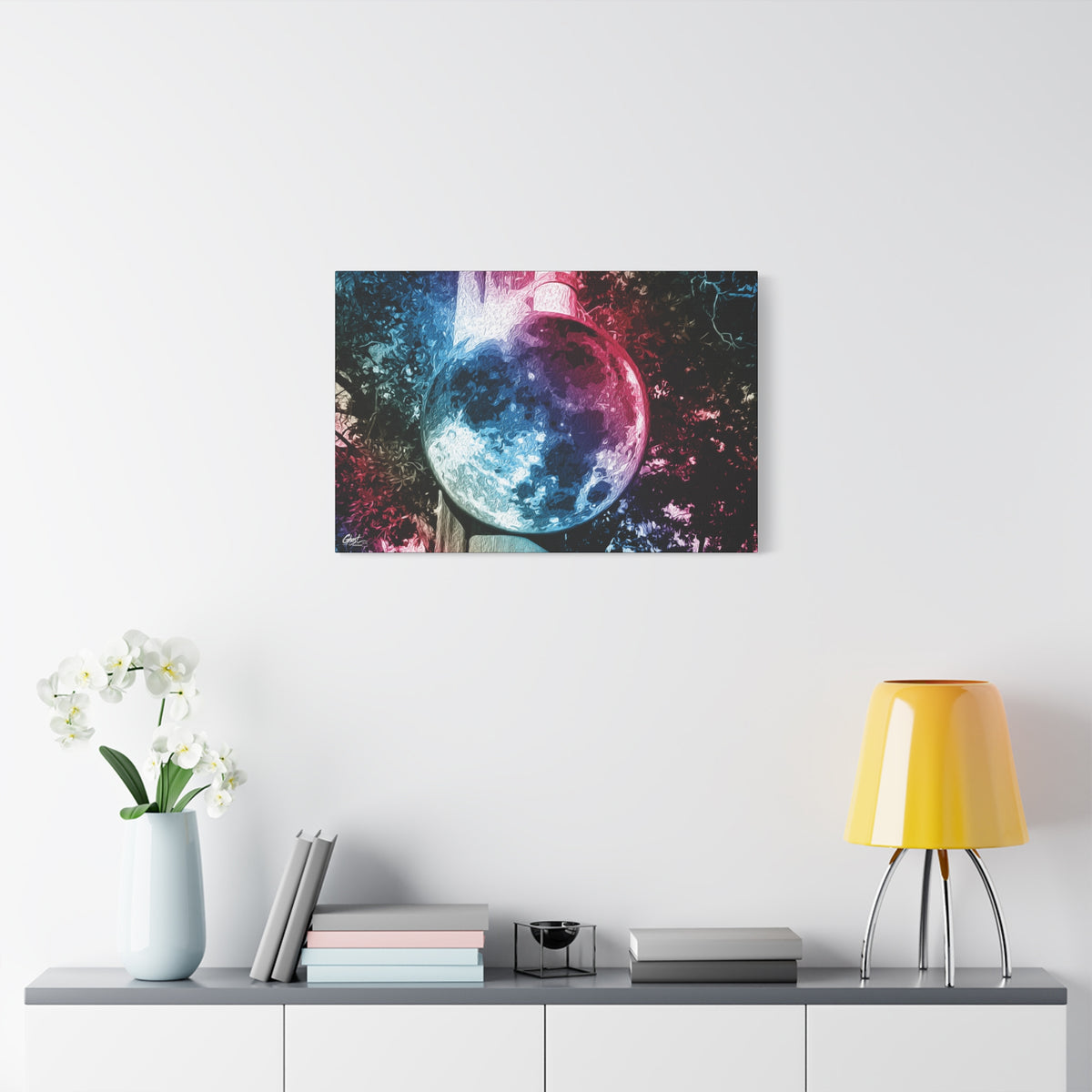 Universe in a Mirror canvas over a console with white flowers, moon-like orb in blue and pink film tones in a surreal sky