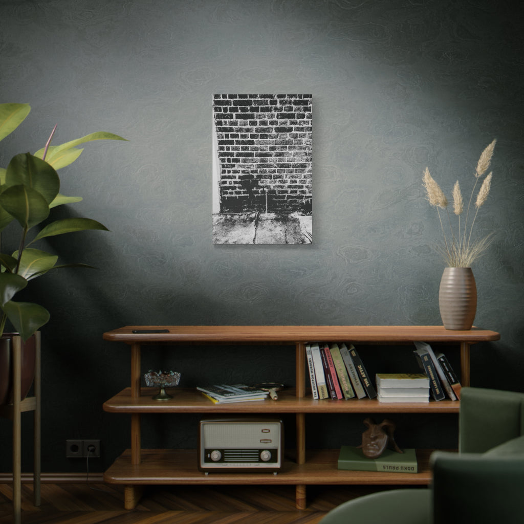 A Little Hiking in Charleston medium canvas above a wooden bookshelf, high-contrast brick wall with a tiny stencil hiker