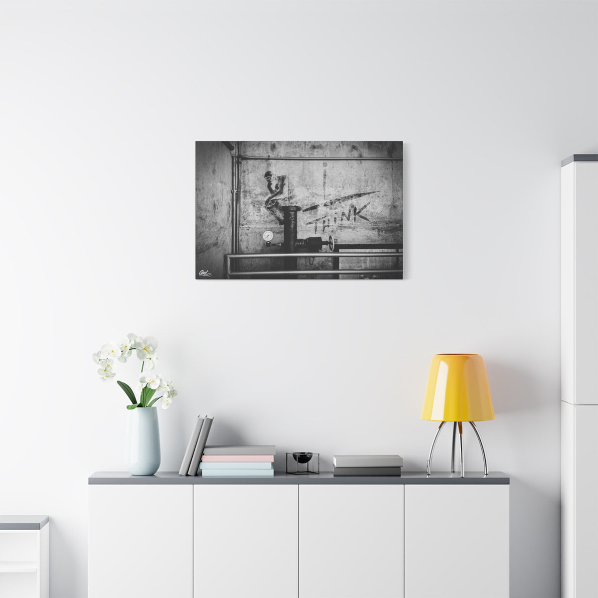 I Overthink medium canvas above a white sideboard and yellow lamp, gritty parking-garage wall with a stenciled THINK