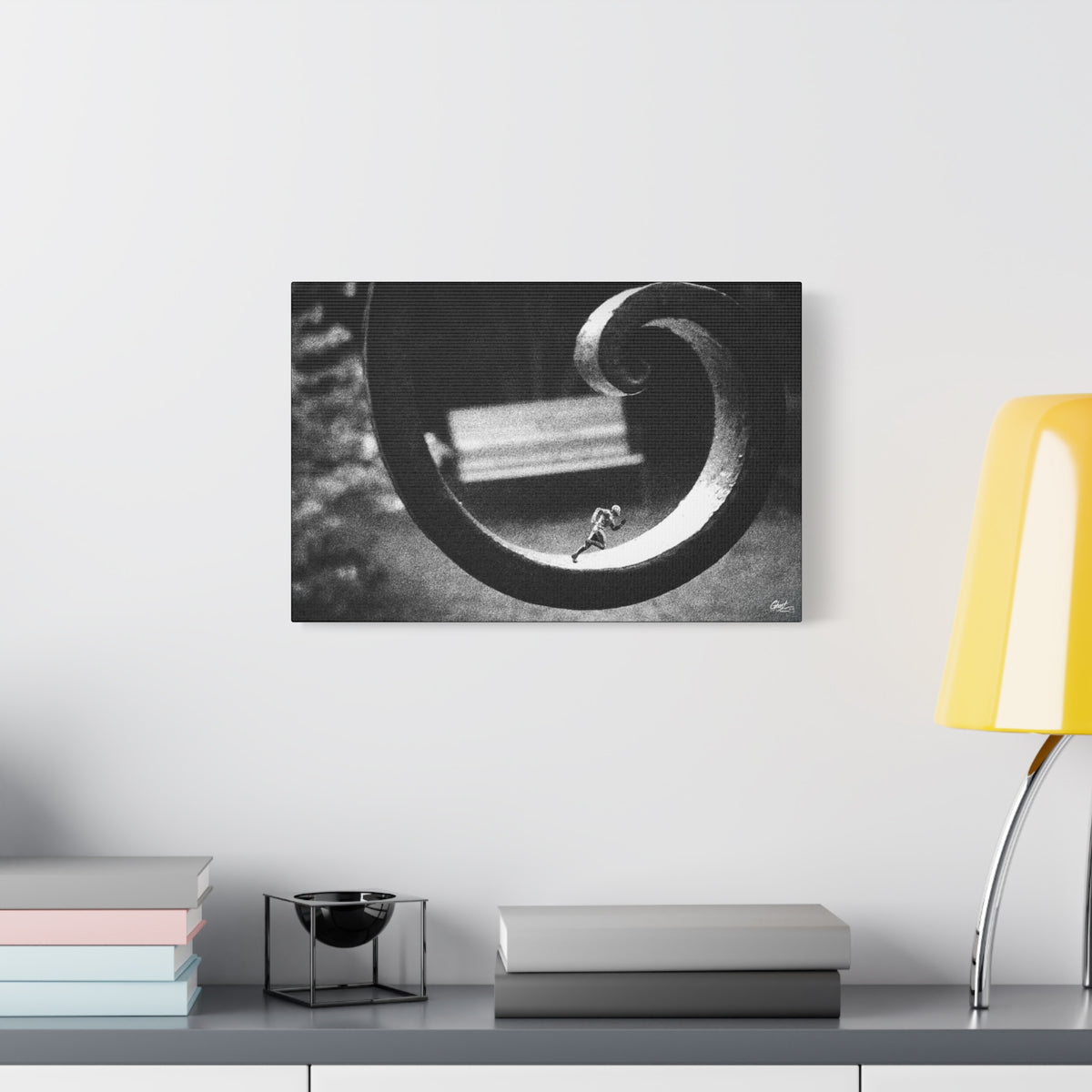 A Man in Charleston large canvas beside a yellow desk lamp, black-and-white Charleston alley ironwork with a miniature figurine mid-stride