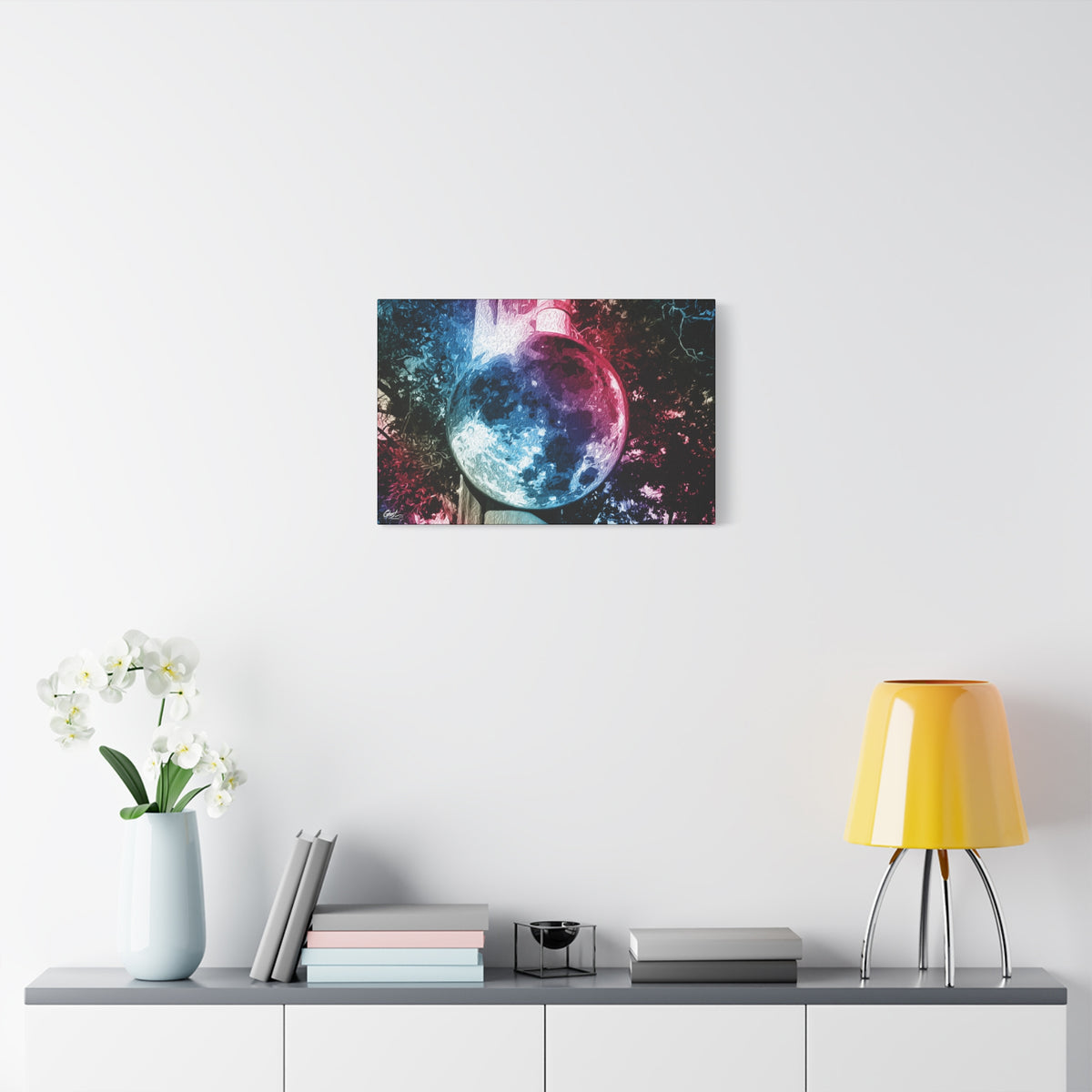 Universe in a Mirror medium canvas on a white wall above a console, glowing mirrored orb floating in a dreamy pink-blue sky
