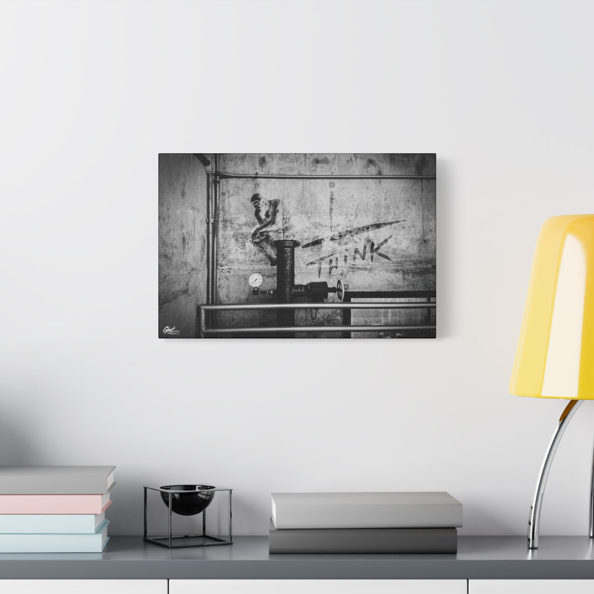 I Overthink oversized canvas beside a yellow desk lamp, stenciled THINK with pipes and gauges on concrete, black and white