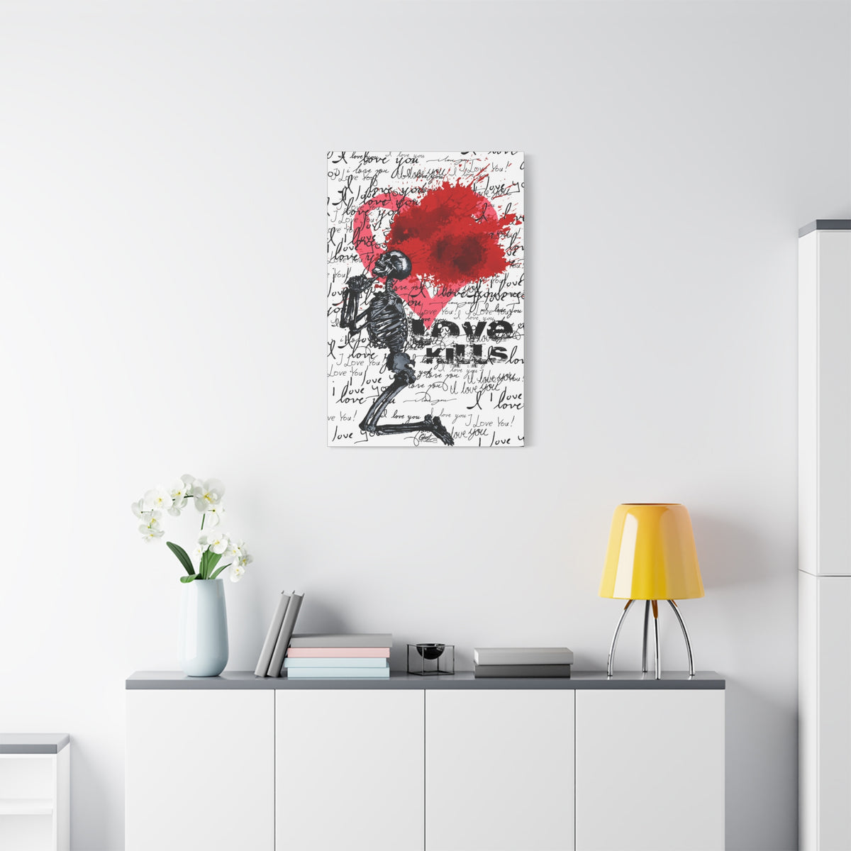 Love Kills small canvas above a white sideboard and yellow lamp, kneeling skeleton before a burst pink and crimson heart