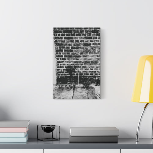 A Little Hiking in Charleston canvas beside a yellow desk lamp, stenciled hiker on a weathered brick wall in black and white