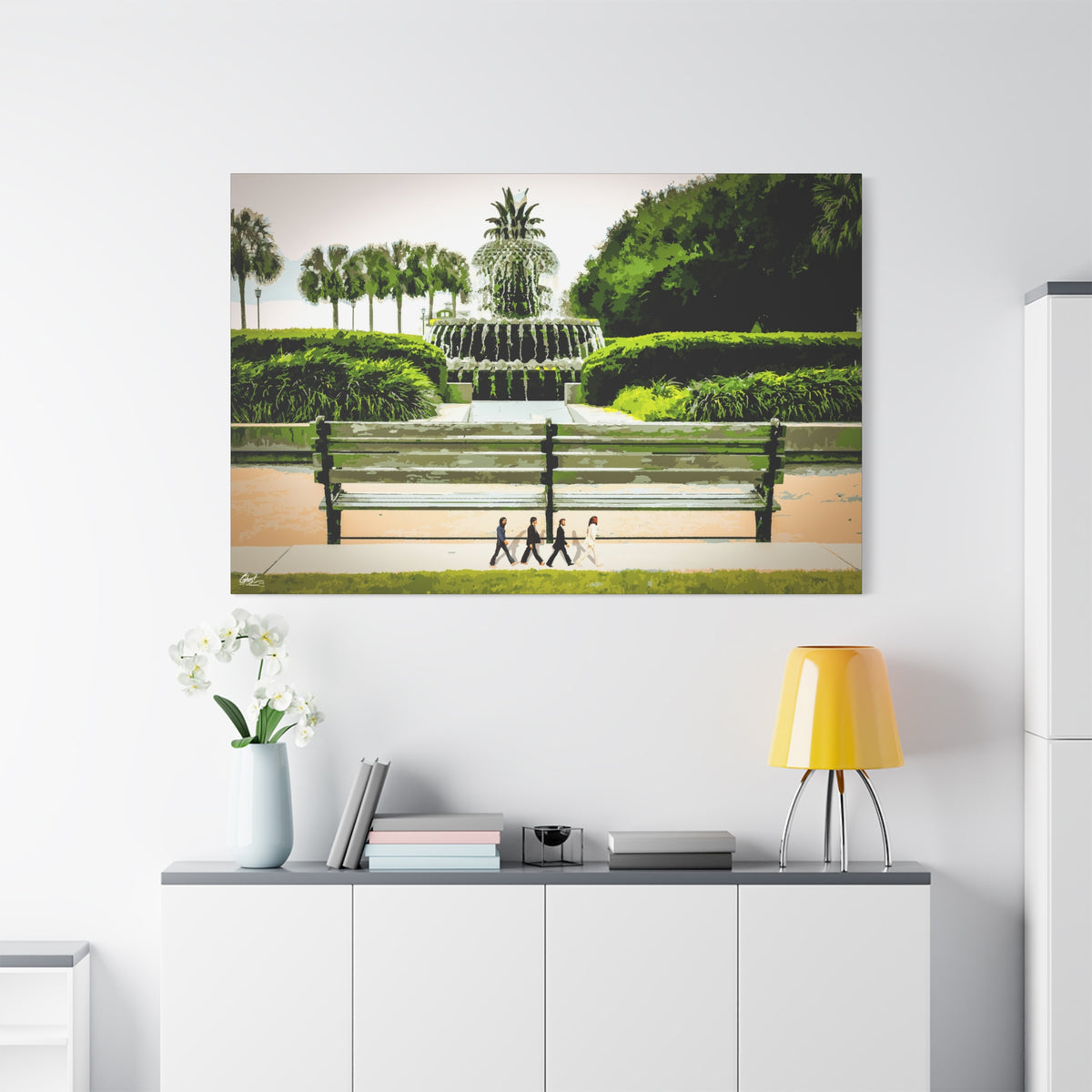 Pineapple Crossing large canvas above a white sideboard and yellow lamp, pineapple fountain and four walkers